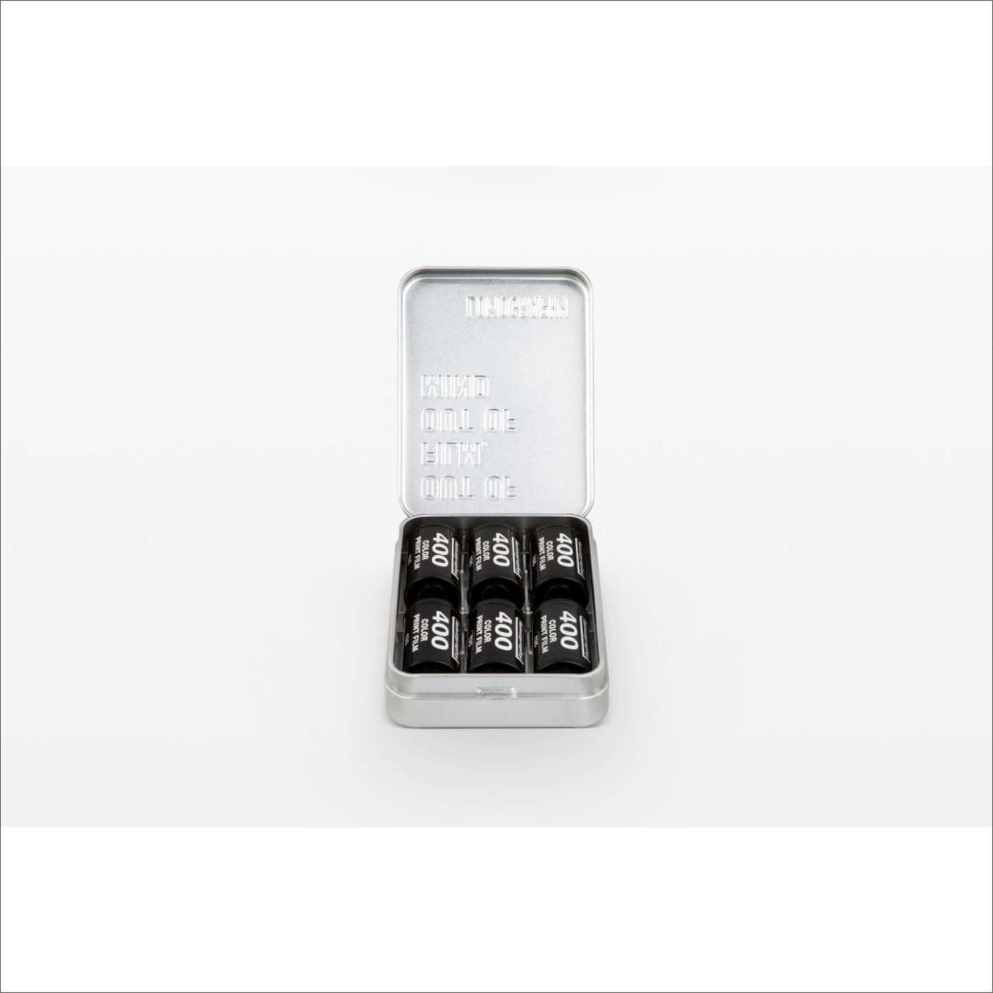 Open tin box containing six black and silver 400DX film rolls on a white background.