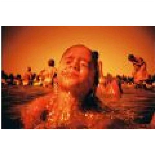 Person enjoying swimming in an orange-hued pool with others in the background on a sunny day