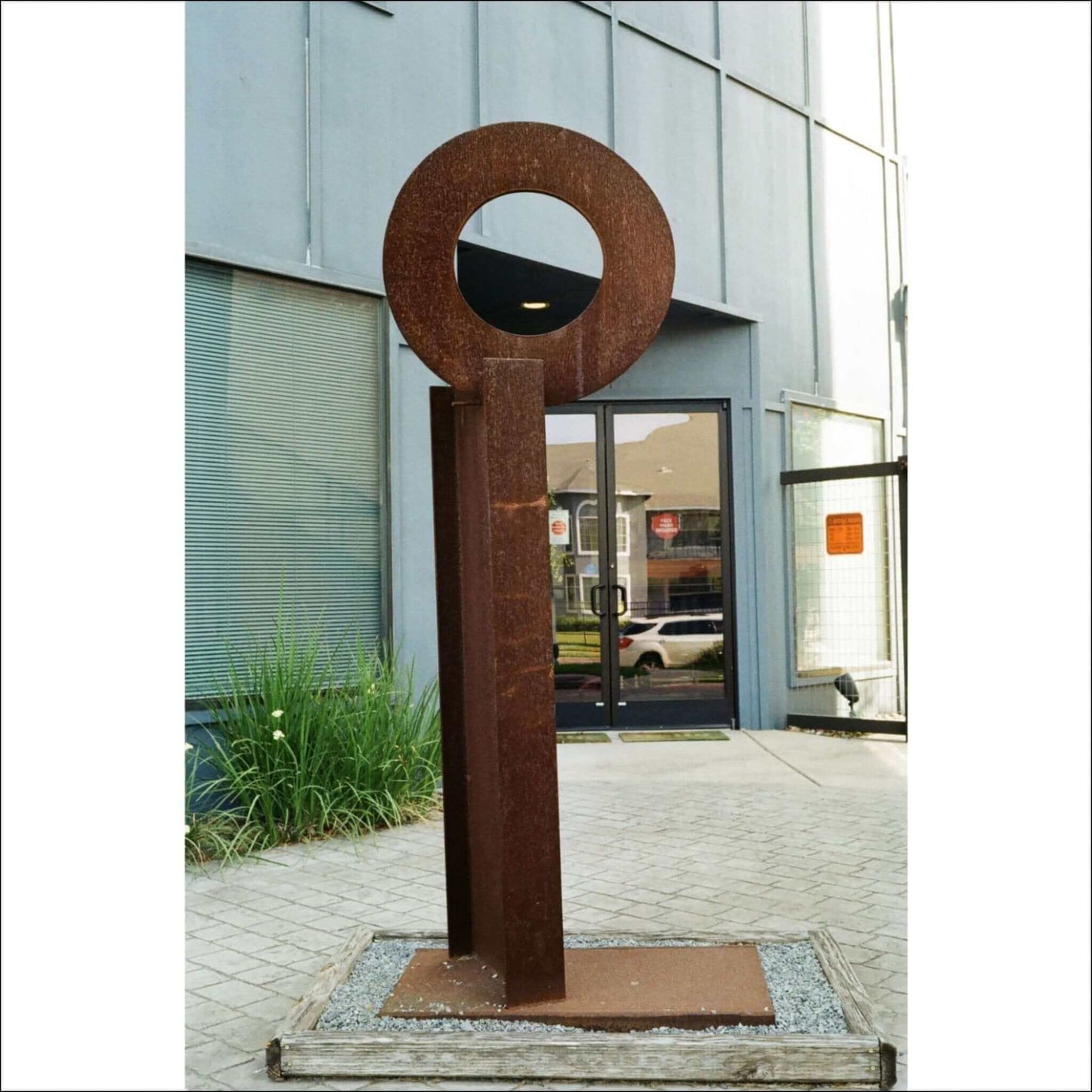 Outdoor modern sculpture with a circular top and vertical base in an urban setting.