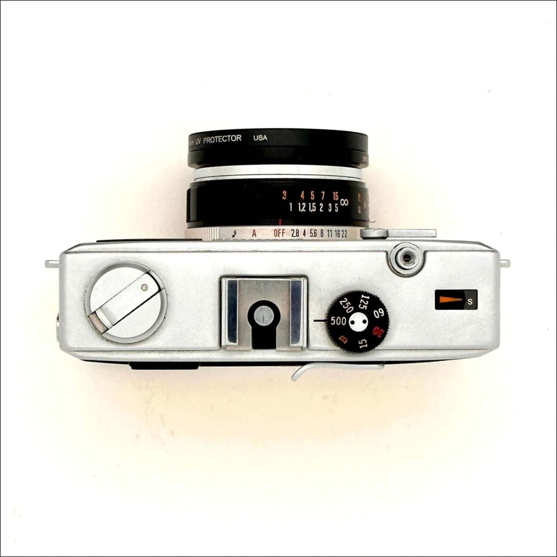 Vintage silver analog camera top view with lens and dials.