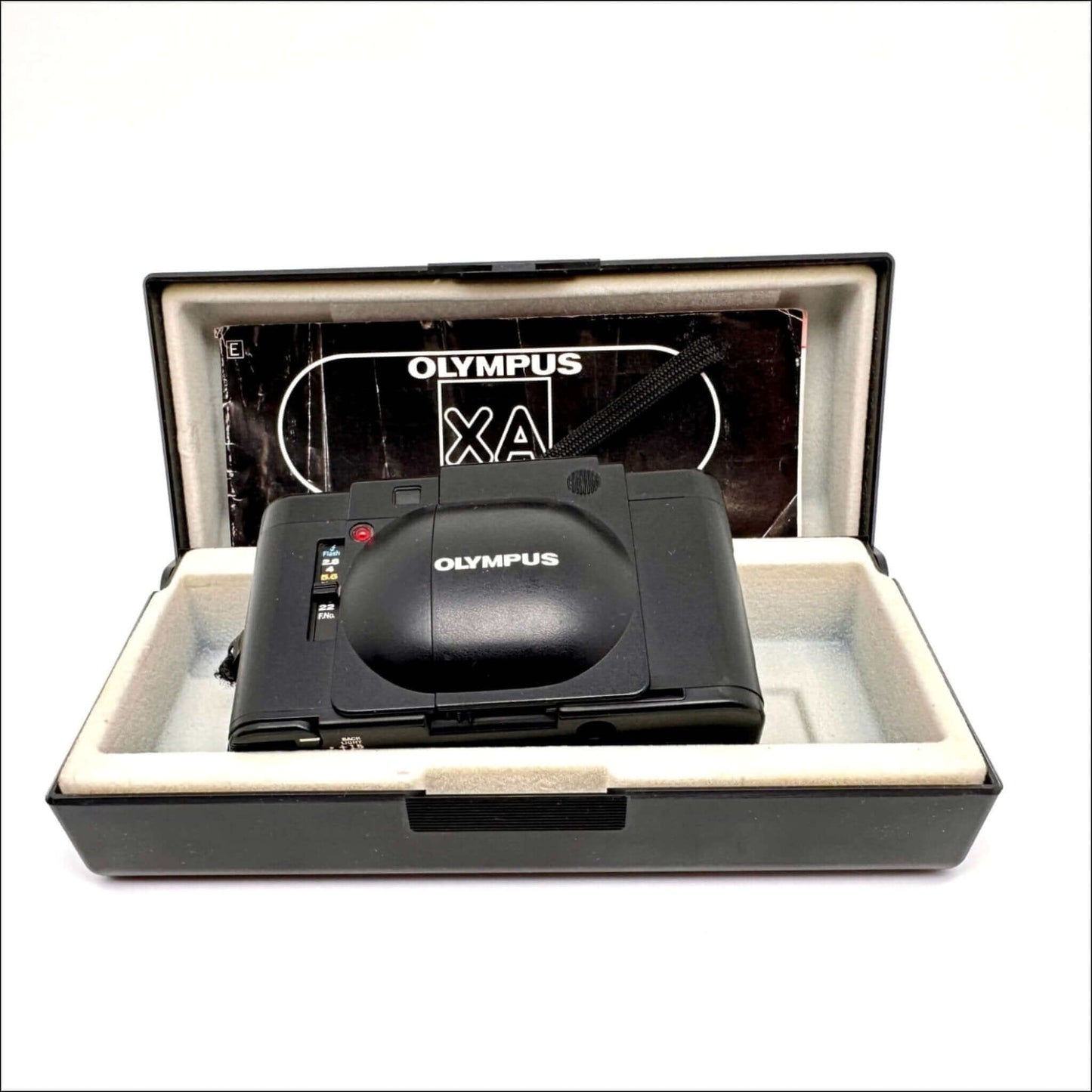 Olympus XA used 35mm vintage film camera in case with manual, showcasing its sleek design and classic features.