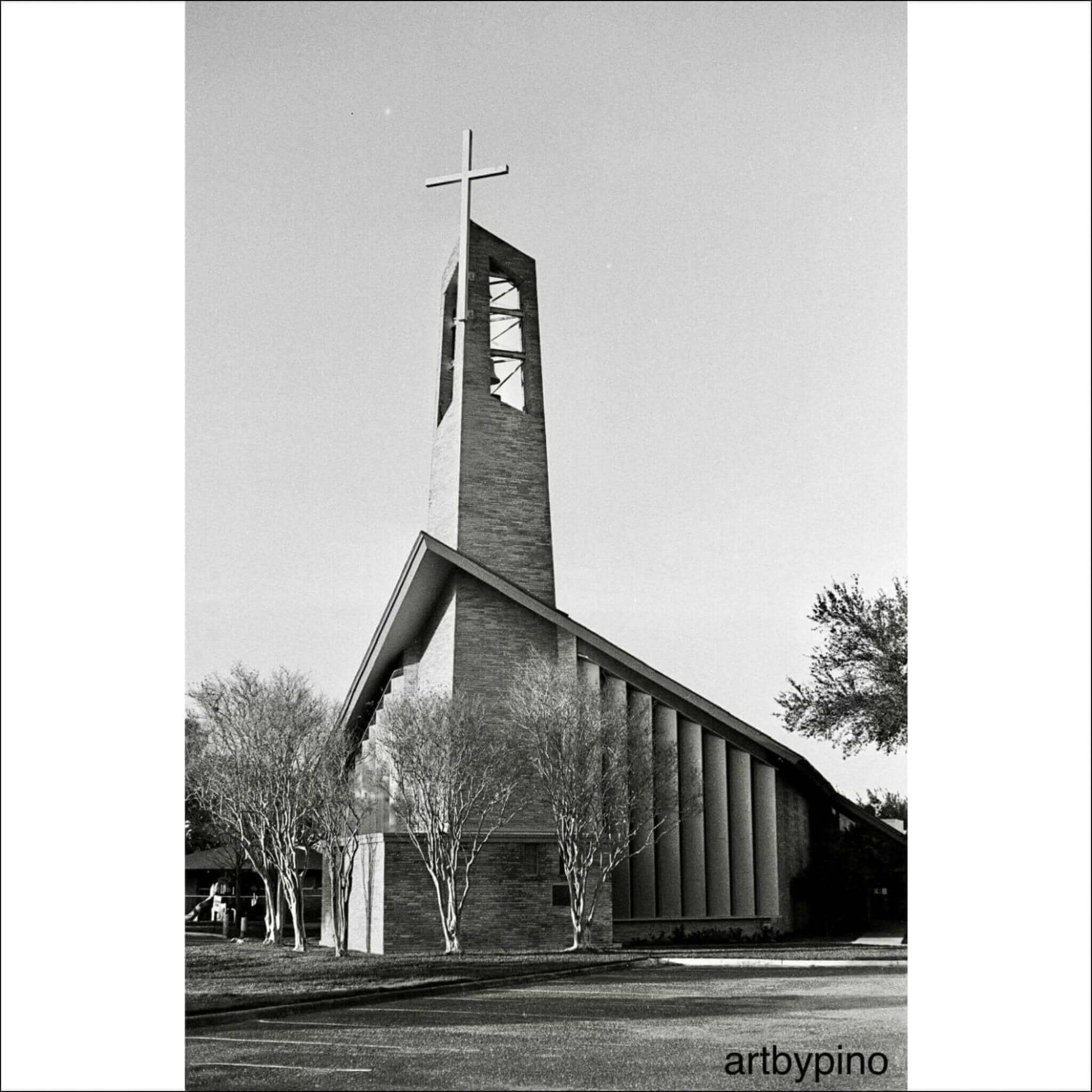 Black and white photograph of a modern church building with a tall cross-topped tower and trees in front.