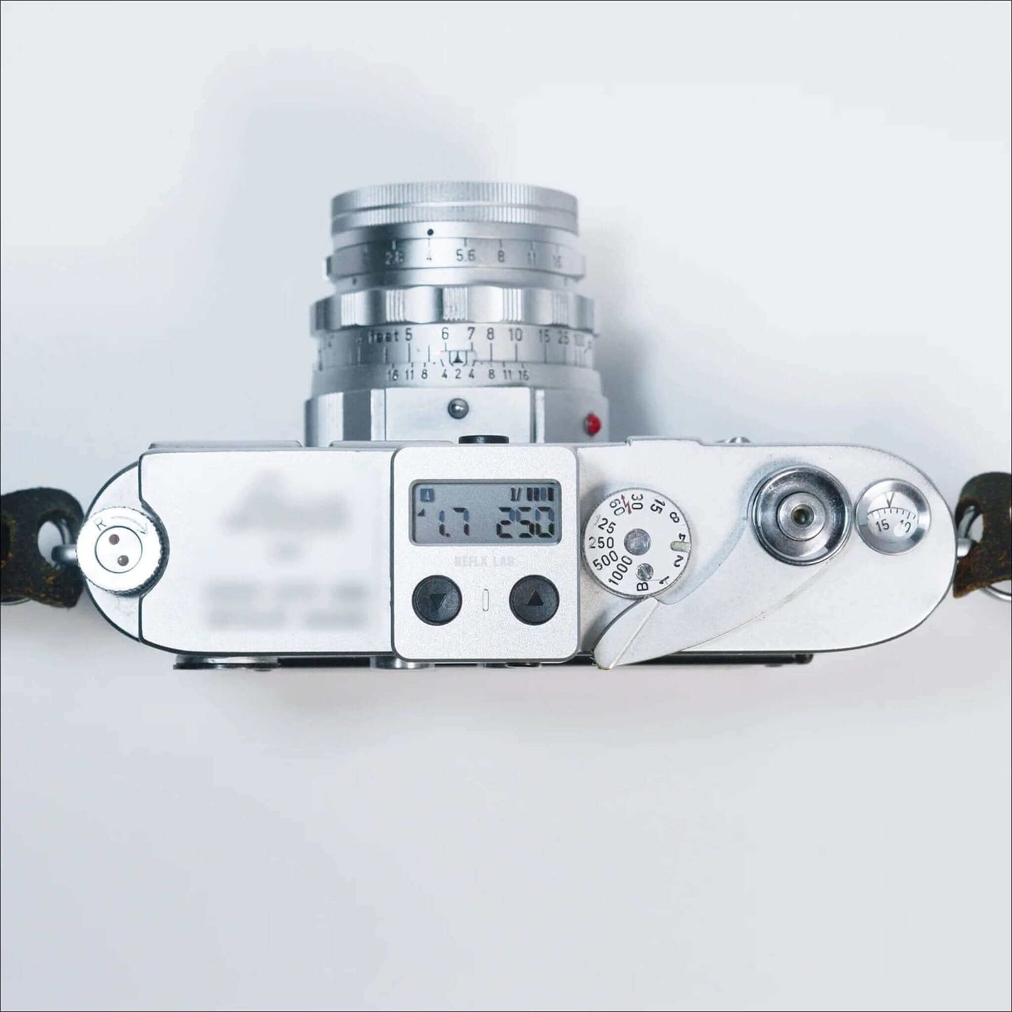 Top view of a vintage silver camera showing control dials and settings on a light background.