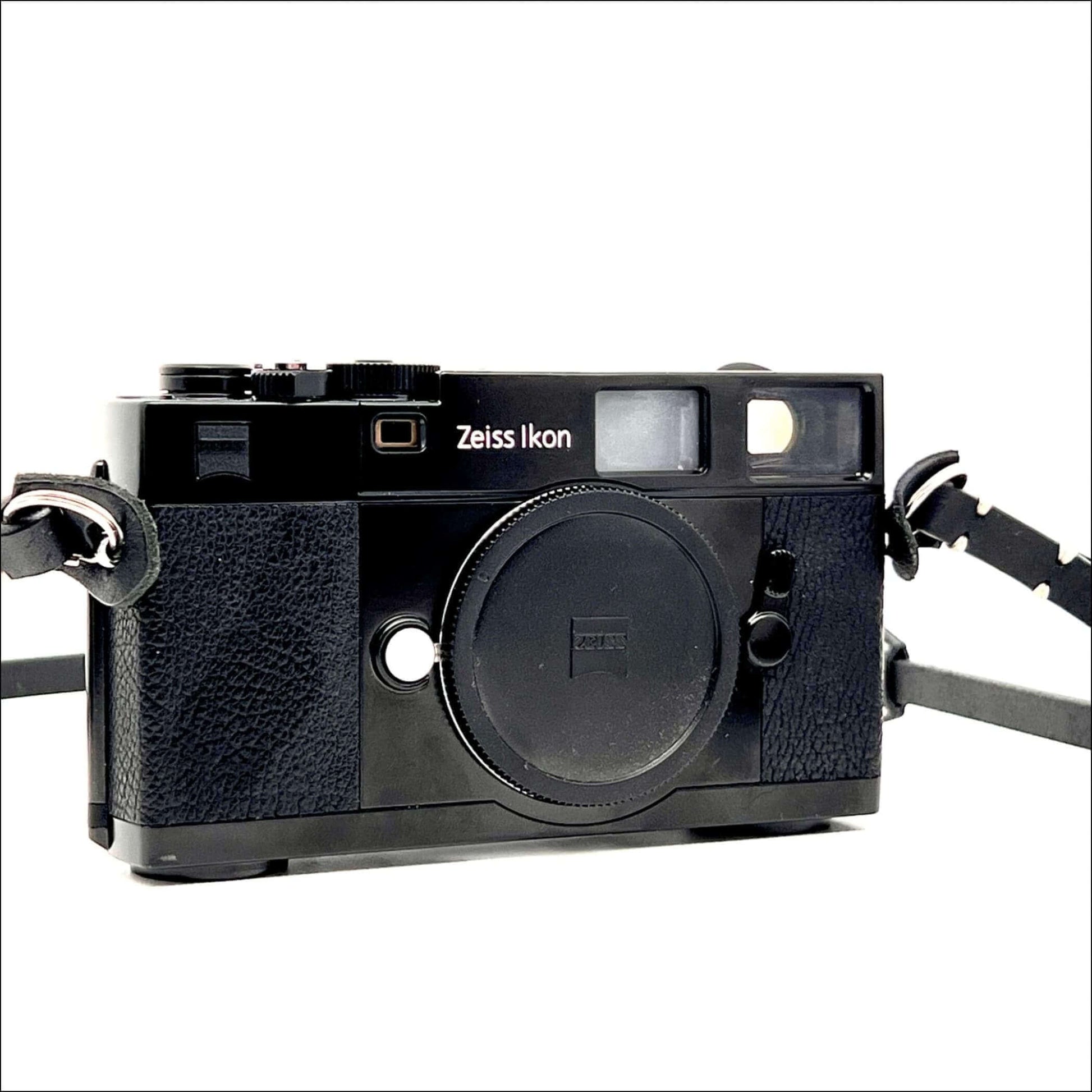 Vintage Zeiss Ikon camera with black body and strap on a white background.